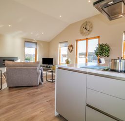 An open kitchen and living area with a stove on the island and sofas facing a TV at The Penthouse in Woodbridge