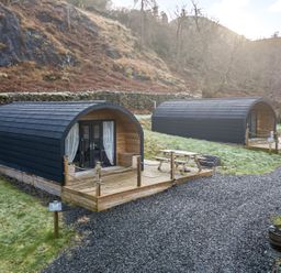 Two wooden camping pods with decks picnic tables and gravel pathways near a hillside at Lovies Place - Crossgate Luxury Glamping Hartsop near Glenridding