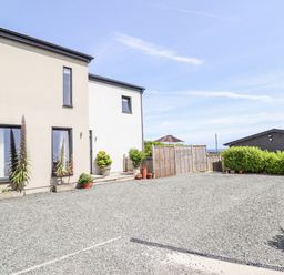 An exterior view of a house with plants and a gravel area at Bryn Mor in Benllech