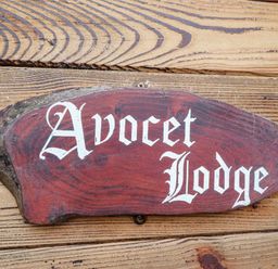 A wooden sign with Avocet Lodge written on it mounted on a wooden wall at Avocet Lodge Tattershall Lakes Country Park