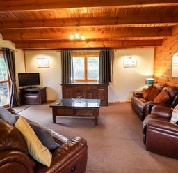 A living room with leather sofas a coffee table a television and wooden ceiling at Avocet Lodge in Tattershall Lakes Country Park