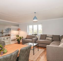 A living room with a gray sofa set a wooden dining table with chairs and plants at Rainbow View in Churchstanton near Churchinford