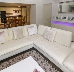 A living room with a white sectional sofa and a dining area with wooden table and chairs visible at The Old Farm House in Redberth near Pentlepoir