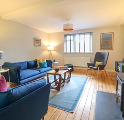 A living room with blue sofas armchair wooden coffee table and floor lamp at The Wardens House in Tregynon near Newtown