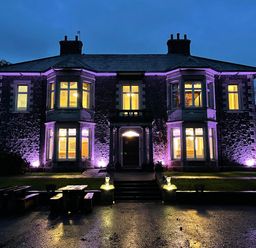 A stone building with illuminated windows and purple lights outside at The Lloyd George in Bontnewydd Gwynedd