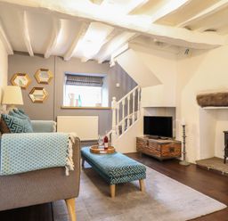 A living room with a sofa ottoman wood stove and TV at 3 Ivy Court in Dolgellau