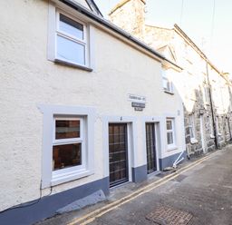 Exterior of stone and stucco houses with windows and doors on a narrow street at Deu-Ddrws in Barmouth