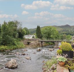 A river with a bridge surrounded by greenery at Riverside Cottage Beddgelert