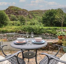 A table set with bowls and glasses near a river at Riverside Cottage in Beddgelert