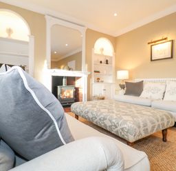 A living room with sofas an ottoman a fireplace and shelves at The Middle House in Southwold