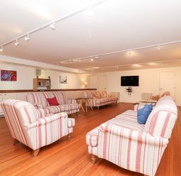 A sitting room with striped sofas wooden floor and a wall-mounted TV at The Old Gymnasium in Southwold