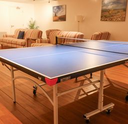 A room with a ping pong table and striped sofas with paintings on the walls at The Old Gymnasium in Southwold