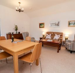 A living room with a wooden dining table and chairs and a seating area with a sofa and armchairs at 6 Granary Court York