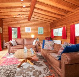 A living room with two brown sofas a wooden coffee table and red curtains at Rocksite in Kirkmichael Perth And Kinross