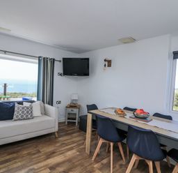 A living room with a sofa and dining table at Sunset Sea View Chalet in Millbrook