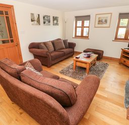 A living room with two brown sofas a wooden coffee table a rug and a television at Ty Melyn in Boncath
