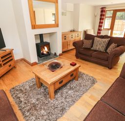 A living room with brown sofas a wooden coffee table and a fireplace at Ty Melyn in Boncath