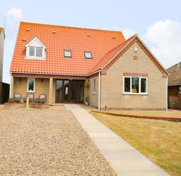 A house with a red tiled roof a gravel driveway and a paved walkway at Drifters in Winterton-On-Sea