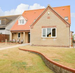 A front view of a brick house with a tiled roof and a lawn at Drifters in Winterton-On-Sea