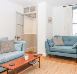 A living room with blue sofas a wooden coffee table and a window at The Cottage on The Square in Chagford