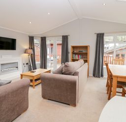 A living room with a sofa coffee table bookshelf dining table and chairs at Highfield Lodge Kirkstone 30 Limefitt Park near Troutbeck