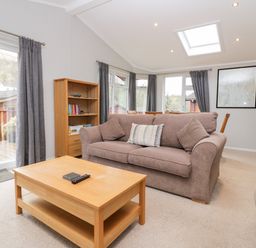 A living room with a sofa coffee table bookshelf and dining table at Highfield Lodge in Kirkstone 30 Limefitt Park near Troutbeck