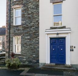 The entrance of a stone house with a blue door and two windows at Carlton House Apartment 1 in Keswick