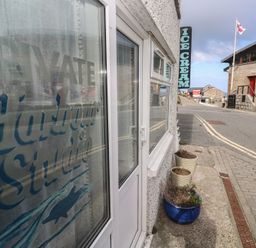 An outdoor view of a sign for Harbour Studio at Sennen Cove