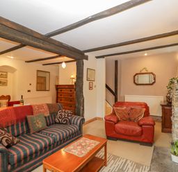 A living room with striped sofa and red armchair near stone fireplace at Field Cottage in Shepton Mallet