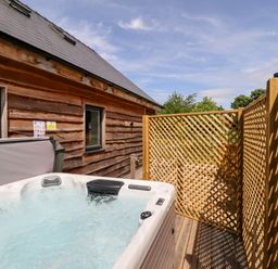 An outdoor hot tub next to a wooden building with lattice fencing around it at Lodge 24 in South Hykeham