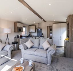 A living room and kitchen area with sofas a coffee table and kitchen appliances at Primrose Lodge in Runswick Bay near Staithes