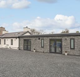 A modern single story house with stone and white walls and gravel driveway at Tan Y Coed - Nasareth in Nasareth near Penygroes