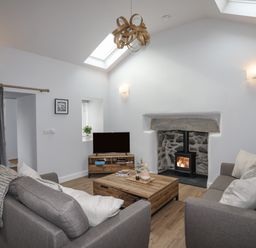 A living room with two sofas a coffee table a fireplace and a television at Tan Y Coed - Nasareth in Nasareth near Penygroes