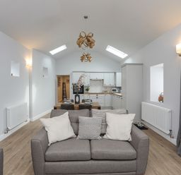 An open plan living room and kitchen with a sofa and dining table at Tan Y Coed - Nasareth Nasareth near Penygroes