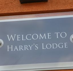 A sign reading welcome to Harrys Lodge mounted on a wooden surface at Harry's Lodge in Ashover