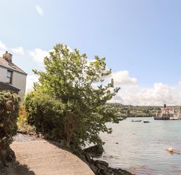 A riverside path next to a house with boats on the water at Ynys Faelog Cottage in Ynys Faelog near Menai Bridge