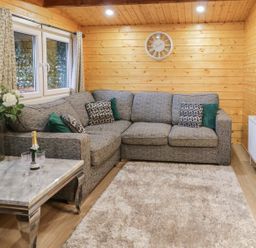 A wooden room with a gray corner sofa cushions and a clock above at Buttermilk Bridge in Dungiven