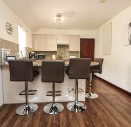 A kitchen with four bar stools at a counter and mosaic tile backsplash at The Old Piggeries in Gulval near Penzance