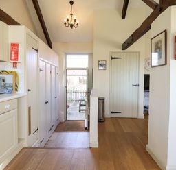 A kitchen with white cabinets microwave fire blanket and door leading outside at The Bull Pen in Colyton