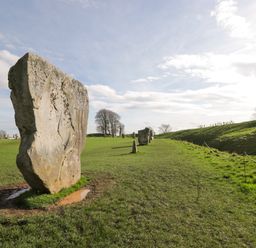 A grassy field with standing stones and a cloudy sky at The Old Bakehouse in Avebury