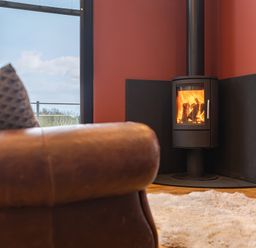 A room with a leather chair a patterned cushion a burning fireplace and a fluffy rug at Stags Mount in Thornton Dale