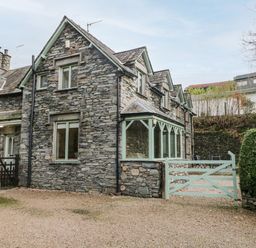 A stone exterior house with multiple windows and a green wooden gate at Scandale Bridge Cottage in Ambleside