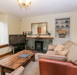 A living room with a sofa coffee table television and fireplace at Scandale Bridge Cottage in Ambleside