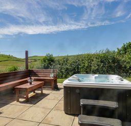 An outdoor area with a hot tub and wooden bench at Holly in Ulverston