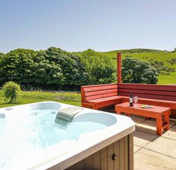 An outdoor area with a hot tub and a wooden seating area at Willow in Ulverston