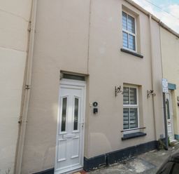 The exterior of a beige terraced house with white door and two windows at Day Cottage in Weymouth