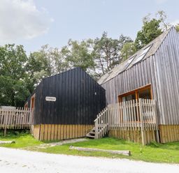 Two wooden cabins with stairs and fencing surrounded by trees at Lodge 6 in Corfe Castle