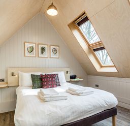 A bedroom with a double bed pillows and folded towels under two skylight windows at Lodge 8 in Corfe Castle