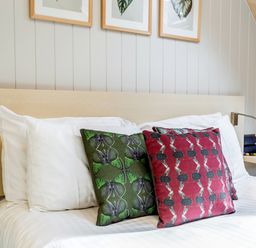 A bed with white pillows and butterfly patterned cushions with wall lamps at Lodge 9 in Corfe Castle