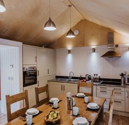 A kitchen with wooden dining table set for four and beige cabinets at Lodge 11 in Corfe Castle